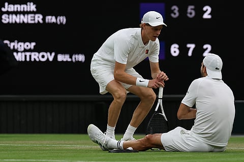 Bulgaria's Grigor Dimitrov (R) speaks with Italy's Jannik Sinner (L) after getting injured during their men's singles fourth round tennis match on the eighth day of the 2025 Wimbledon Championships at The All England Lawn Tennis and Croquet Club in Wimbledon, southwest London, on July 7, 2025.