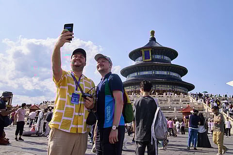 Tourists take a selfie at the Temple of Heaven as they take a half-day tour offering by a travel agency Trip.com Group, in Beijing on June 15, 2025.