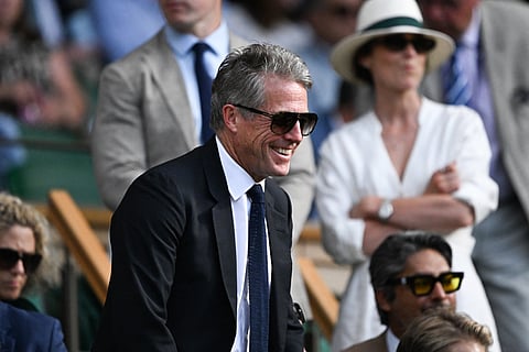 British actor Hugh Grant reacts in the royal box of Centre Court during the men's singles quarter-final tennis match between Serbia's Novak Djokovic and Italy's Flavio Cobolli on the tenth day of the 2025 Wimbledon Championships at The All England Lawn Tennis and Croquet Club in Wimbledon, southwest London, on July 9, 2025.