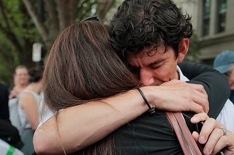 US State Department employee (L) who was recently laid off is hugged at a rally in support federal workers near the Harry S. Truman Federal Building on July 11, 2025 in Washington, DC. x