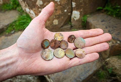 National Trust's Nature Engagement Officer, Cliff Henry, holds coins that were left by tourists in the cracks of the stones at the Giant's Causeway, a Unesco World Heritage Site, near Bushmills in Northern Ireland, on July 8, 2025.