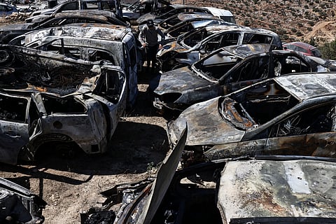 A Palestinian man walks amid destroyed cars that were set alight during a reported late-night attack by Israeli settlers on the village of Burqa, east of Ramallah in the Israeli-occupied West Bank on July 15, 2025.