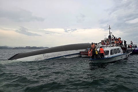 This handout photograph taken on July 19, 2025 and released by the Vietnam News Agency (VNA) shows relief personnel gathered around a capsized tourist boat (L) during a search and rescue operation in the Ha Long Bay, Quang Ninh province.