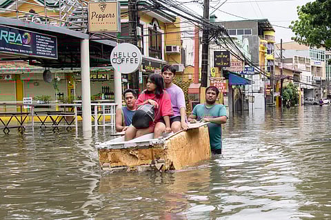 People ride on makeshift raft at a village in Cainta town, east of Manila on July 22, 2025, in the aftermath of monsoon rains.
