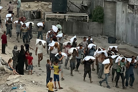 Men walk carrying sacks of flour that were taken from a raided truck carry sacks of flour after raiding a truck that was carrying foodstuffs, in Khan Yunis in the southern Gaza Strip.