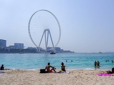 People sunbathe along the Marina beach near the Ain Dubai Ferris wheel.