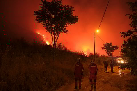 Firefighters attempt to extinguish a wildfire as smoke and flames rise from a forested area in the Gursu district of Bursa early on July 27, 2025.