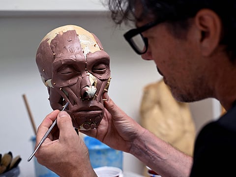 Dutch artist Alfons Kennis works on a model representing a prehistoric human skull in his workshop in Arnhem, on July 3, 2025.