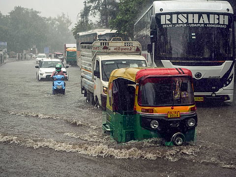 Commuters make their way through a waterlogged street during heavy rainfall, in New Delhi on Tuesday, July 29, 2025.