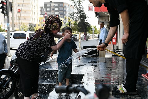 A woman puts water of the face of her child during an extreme heatwave at Silopi district in Sirnak on July 30, 2025.