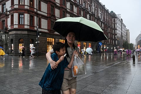 People protect themselves from the rain with umbrellas during the passage of Typhoon Co-May in Shanghai on July 30, 2025