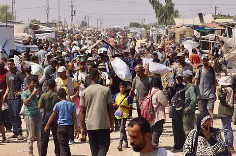 Palestinians carry humanitarian aid they received at the Rafah corridor as they walk in the Mawasi area of Rafah in the southern Gaza Strip on July 30, 2025.