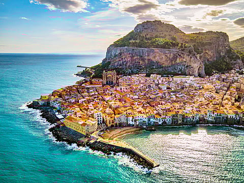 A drone view from above at the old town of Cefalu at sunset, medieval village of Sicily island, Province of Palermo, Italy. Europe. Cathedral of Cefalu