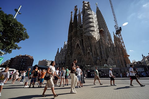 Tourists walk past the Sagrada Familia basilica in Barcelona, on August 2, 2025.