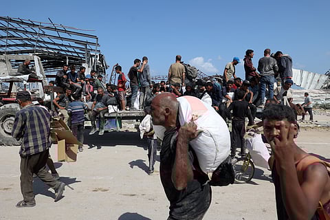 Palestinians transport bags as they return from a food distribution point run by the US and Israeli-backed Gaza Humanitarian Foundation (GHF) group, near the Netsarim corridor in the central Gaza Strip on August 3, 2025.