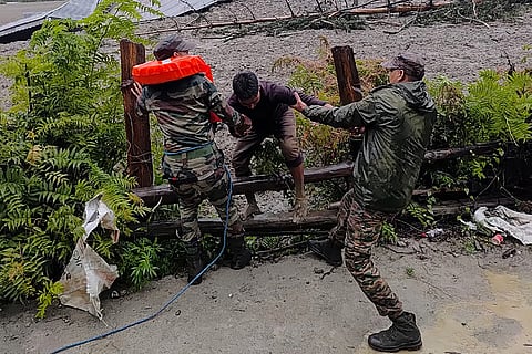 This handout photograph taken on August 5, 2025 and released by the Indian Army shows security personnel rescuing a local resident (C) from dense sludge during a search and rescue operation after a cloudburst caused a massive mudslide in India's Uttarakhand state.