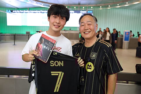 Jun Kwon (L) and his father Hojin Kwon, supporters of South Korean football player Son Heung-min, pose with LAFC jersey as they wait for his arrival at the Los Angeles International Airport in Los Angeles, California on August 5, 2025.
