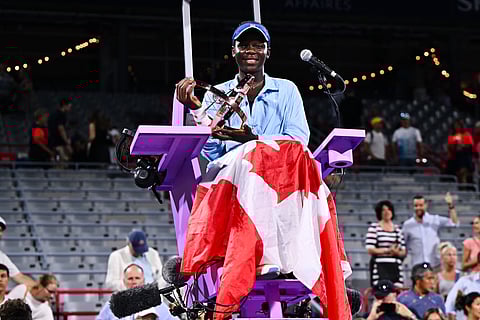 Victoria Mboko of Canada poses with a Canadian flag and the trophy at the umpire's chair following her victory against Naomi Osaka of Japanin Montreal, Quebec, Canada.