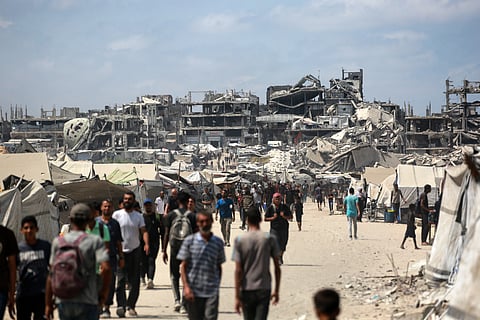 Palestinians walk along a street near war-damaged buildings in Gaza City on August 8, 2025.