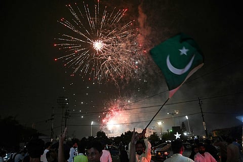A man waves a flag of Pakistan as people watch a firework displayed in front of the National Stadium during Pakistan's 78th anniversary of Independence Day celebrations in Karachi on August 14, 2025.