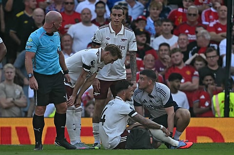 Arsenal's English defender Ben White (C) reacts to picking up an injury during the English Premier League football match against Manchester United at Old Trafford in Manchester, north west England, on August 17, 2025.