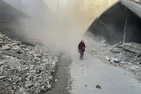 A Palestinian young woman rushes away from the site of Israeli air strikes on a six-storey building in the Saftawi neighborhood west of Jabalia in the northern Gaza Strip on August 19, 2025.