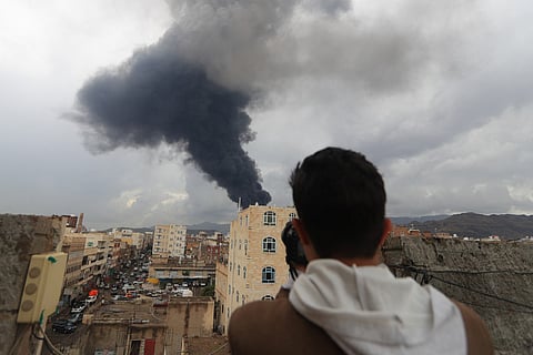 A photojournalist takes a picture of smoke after an Israeli air strike on Yemen's Houthi-held capital Sanaa on August 24, 2025.