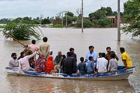 Flood-affected people evacuate on a boat amid rising water levels after heavy rainfall in the Haqu Wala village of Pakistan's Kasur district on August 24, 2025.