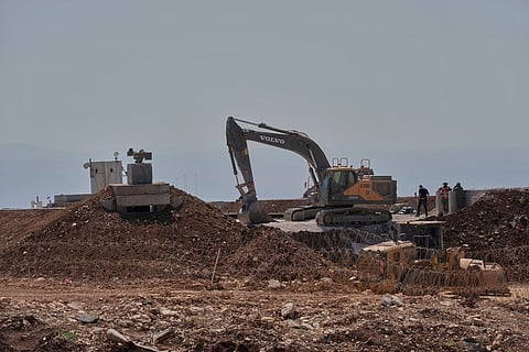 Workers stand beside a bulldozer at one of five new Israeli army positions built inside Lebanese territory along the road between Houla and Kfar Kila following airstrikes and a ground offensive that destroyed nearby villages, southern Lebanon, Wednesday, August 20, 2025.