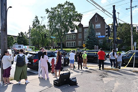 Bystanders and media look on near the scene of a shooting at Annunciation Catholic School in Minneapolis, Minneosta, on August 27, 2025.