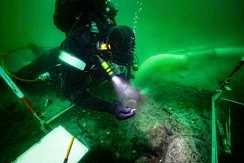 A diver excavates an 8,500-year-old Stone Age coastal settlement, submerged by sea level rise in the Bay of Aarhus, Denmark.