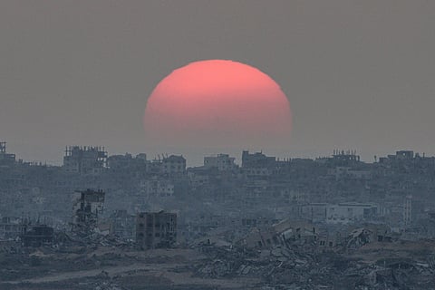 The sun sets behind buildings destroyed during Israeli ground and air operations in the Gaza Strip, as seen from southern Israel, Tuesday, August 26, 2025.