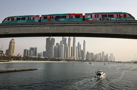 A train runs over a section of Dubai's Palm Monorail, with a backdrop of the city's high rise buildings