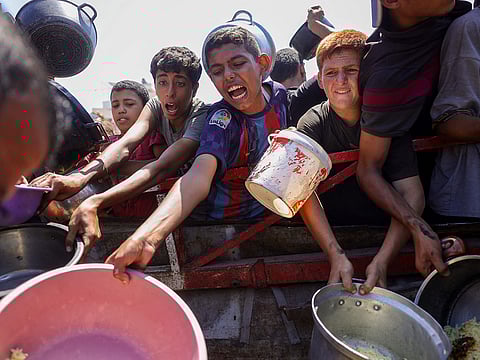 People try to get rice from a charity kitchen providing food for free in the west of Gaza City, on August 28, 2025, as the war between Israel and the Hamas militants movement continues.
