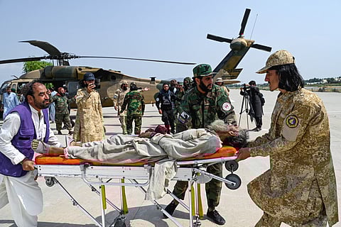 Afghan volunteers and Taliban security personnel carry an earthquake victim evacuated by a military helicopter from the Nurgal district of Kunar province, after his arrival for medical assistance in Jalalabad on September 1, 2025.