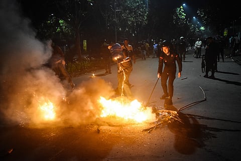 A police officer extinguishes a fire set by protesters in front of the Bekasi Metro Police headquarters in Bekasi, West Java on September 1, 2025, amid clashes linked to a wave of protests that have spread across major cities, after footage went viral showing a police armoured vehicle hitting a motorcycle taxi driver during an earlier demonstration.