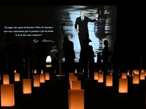 People queue to see the coffin of late Italian fashion designer Giorgio Armani lying-in state for two days at the Armani Theatre in Milan as a picture of him is seen on a screen, on September 6, 2025.