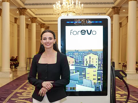 Anna Tsenter poses for a photo in front of a charging station at the event in Dubai on Tuesday night.