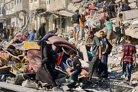 Palestinians retrieve items from the rubble of a destroyed building following overnight Israeli army bombardment on al-Shati camp for Palestinian refugees, west of Gaza City, on September 12, 2025.
