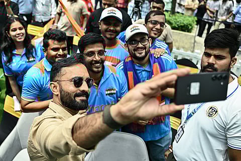 Former Indian cricketer Dinesh Karthik (L) takes a selfie with cricket fans during the unveiling of the ICC Women's Cricket World Cup Trophy in Bengaluru on September 13, 2025.