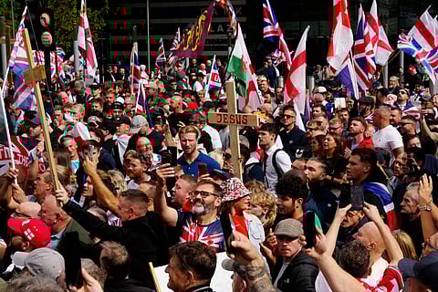 Supporters of British far-right activist Tommy Robinson, whose real name is Stephen Yaxley-Lennon, walk with Union flags and St George's cross and Welsh flags and Christian crosses through central London during a 'Free speech' march, on September 13, 2025.