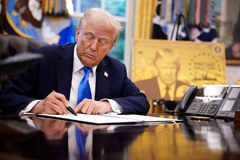 President Donald Trump signs an executive order in the Oval Office at the White House.