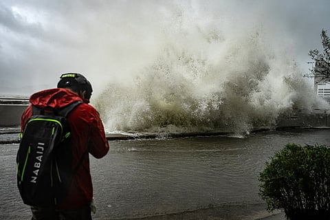 A journalist captures waves crashing into a promenade along Heng Fa Chuen as Super Typhoon Ragasa hits Hong Kong.
