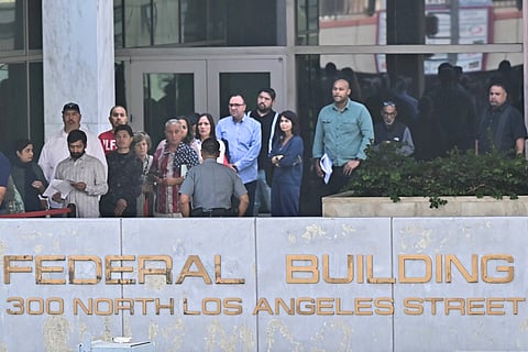 People wait in line to enter the Federal Building in Los Angeles, California on October 1, 2025, where services are experiencing significant disruptions due to the federal government shutdown, as essential workers continue working without pay and non-essential federal workers are furloughed.