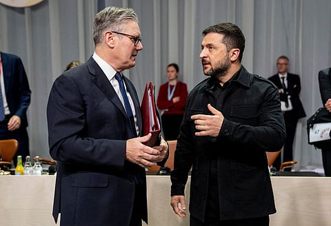 Britain's Prime Minister Keir Starmer (L) and Ukraine's President Volodymyr Zelensky talk during a working session of the 7th European Political Community (EPC) Summit at the Bella Center in Copenhagen on October 2, 2025.