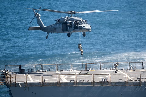 From above, MH-60S helicopters equipped with laser-based detection systems sweep the surface to identify floating or shallow mines. Illustrative image.