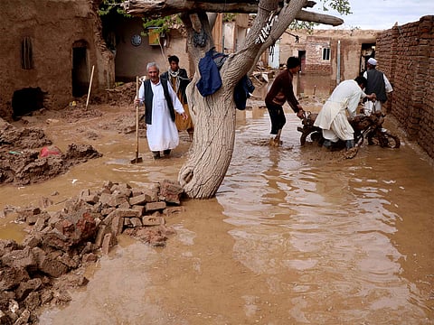 Residents clear debris and wade through floodwater after heavy rains and flash floods hit parts of Afghanistan.