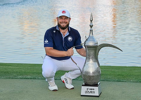 Tyrrell Hatton poses on the 18th green with the Dallah Trophy.