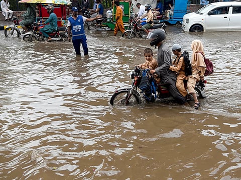 Commuters negotiate a flooded street after heavy monsoon rains in Lahore.