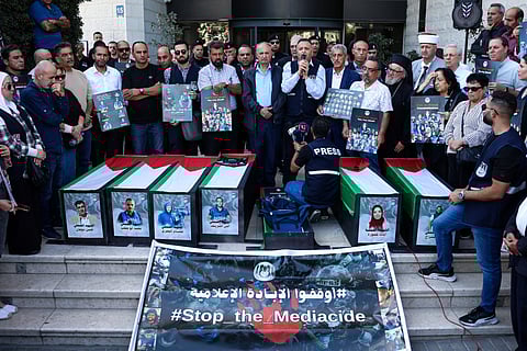 Palestinian journalists and local officials gather around symbolic coffins and portraits of media workers killed in Israeli fire, as they mark two years since the Gaza war erupted during a rally calling for an end to attacks on journalists and for accountability, organised by the Palestinain Journalists Syndicate in Ramallah city in the occupied West Bank on October 8, 2025.